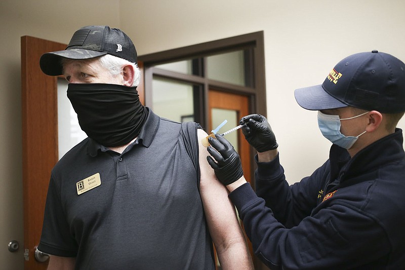Bentonville Fire Department Paramedic Josh Davis (right) administers a covid-19 vaccine to Randy Gully, Bentonville city building inspector (left), Friday at the Bentonville City Hall in Bentonville. The Bentonville Fire Department administered 150 vaccines to city employees at various city properties in Bentonville. Check out nwaonline.com/210312Daily/ for today's photo gallery. 
(NWA Democrat-Gazette/Charlie Kaijo)