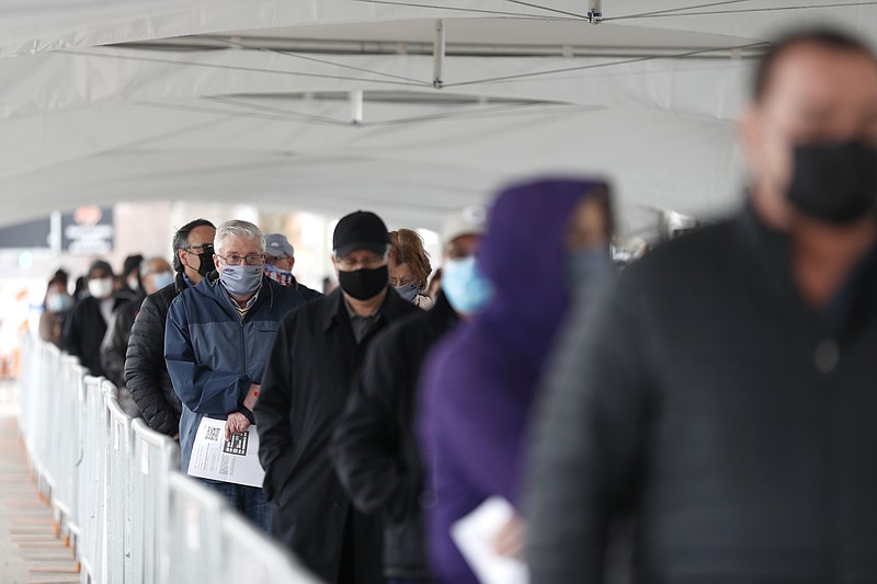 FILE - In this March 10, 2021, file photo, people wait in line at the check-in area to enter the United Center mass covid-19 vaccination site in Chicago. (AP Photo/Shafkat Anowar, File)