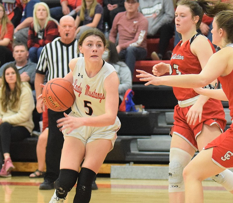 RICK PECK/SPECIAL TO MCDONALD COUNTY PRESS McDonald County's Sydney Killion drives past Carl Junction's Destiny Buerge (23) and Hannah Lee during the Lady Mustangs 56-34 loss in the Missouri class 5 Sectional 6 Basketball Championships held on March 10 at MCHS.