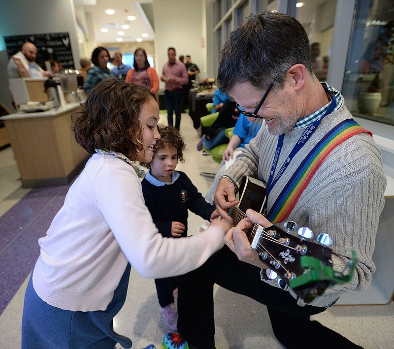 NWA Democrat-Gazette/ANDY SHUPE
Troy Schremmer (right), early childhood music and movement teacher at The New School in Fayetteville, plays music and sings Thursday, Nov. 21, 2019, with a little help from Sydney Johnson, 7, (left) and her sister, Tori Johnson, 4, during a holiday open house at Arkansas Children's Northwest Hospital in Springdale. The event featured live entertainment, food, story time and a visit from Santa Claus.
