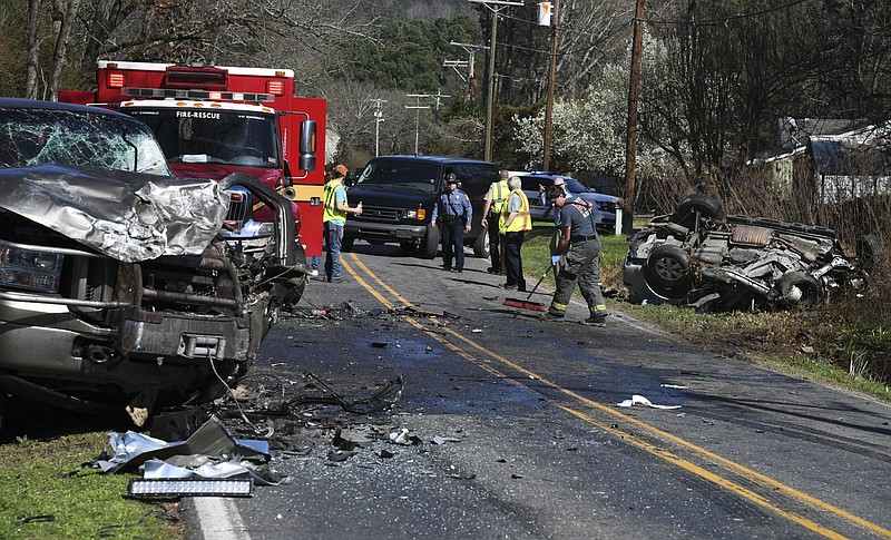 A Piney Fire Department firefighter sweeps debris from Thornton Ferry Road Monday afternoon after a fatal four-vehicle collision. Several of the vehicles involved in the collision are visible on the sides of the roadway. - Photo by Grace Brown of The Sentinel-Record