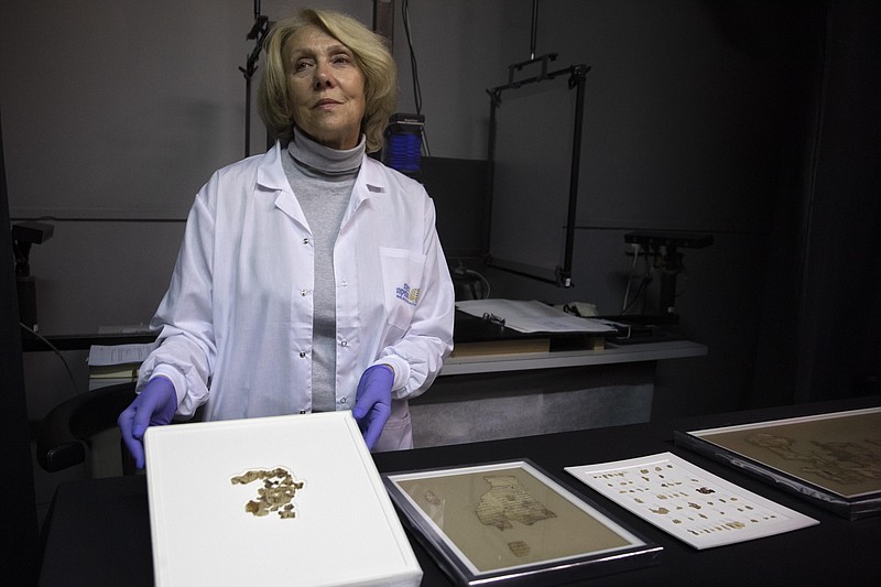 Israel Antiquities Authority conservator Tanya Bitler shows newly discovered Dead Sea Scroll fragments at the Dead Sea scrolls conservation lab in Jerusalem, Tuesday, March 16, 2021. Israeli archaeologists on Tuesday announced the discovery of dozens of new Dead Sea Scroll fragments bearing a biblical text found in a desert cave and believed hidden during a Jewish revolt against Rome nearly 1,900 years ago. (AP Photo/Sebastian Scheiner)