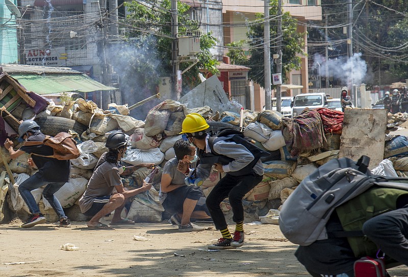 Armed riot policemen charge after firing teargas a rubber bullets as anti-coup protesters abandon their makeshift barricades and run in Yangon, Myanmar on Tuesday. - AP Photo