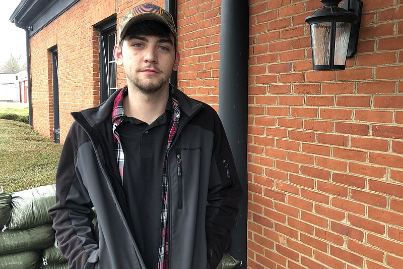 Nico Straughan, 21, poses for a photo on Wednesday, March 17, 2021, outside his family's gun shop in Woodstock, Ga. Straughan said he went to high school with shooting suspect, Robert Aaron Long, and described Long as "super nice, super Christian" and "very quiet." He said Long walked around high school with a Bible. (AP Photo/Sudhin S. Thanawala)