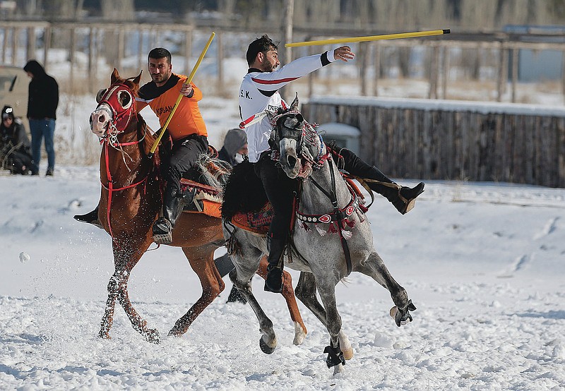 A rider throws the javelin during a game of Cirit, a traditional Turkish equestrian sport that dates back to the martial horsemen who spearheaded the historical conquests of central Asia's Turkic tribes, between the Comrades and the Experts local sporting clubs, in Erzurum, eastern Turkey, Friday, March 5, 2021. The game that was developed more than a 1,000 years ago, revolves around a rider trying to spear his or her opponent with a "javelin" - these days, a rubber-tipped, 100 centimeter (40 inch) length of wood. A rider from each opposing team, which can number up to a dozen players, face each other, alternately acting as the thrower and the rider being chased. Cirit was popular within the Ottoman empire, before it was banned as in the early 19th century. However, its popularity returned as is now one of many traditional sports encouraged by the government and tournaments are often arranged during festivals or to celebrate weddings. (AP Photo/Kenan Asyali)