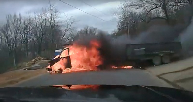 In this screenshot from a Fayetteville police dash cam video, a flaming vehicle rolled down a steep driveway and past a police officer while responding to a call on March 10, 2021.