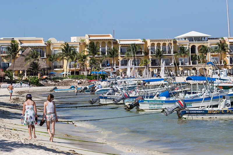 People walk along the beach in Playa del Carmen, Mexico, in a 2017 photo. With covid-19 putting a huge dent in travel, some resorts are offering special deals to entice more travelers. (Bloomberg/Brett Gundlock)