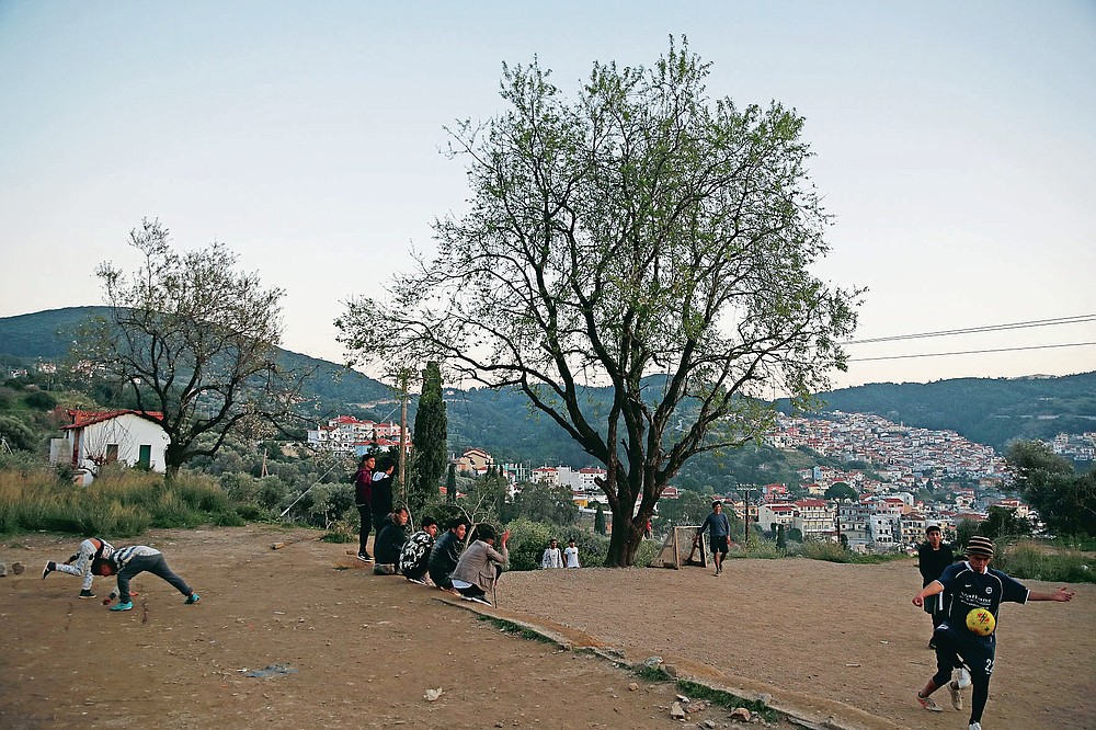 Migrants play soccer outside the perimeter of the overcrowded refugee camp at the port of Vathy on the eastern Aegean island of Samos, Greece, Tuesday, Feb. 23, 2021. On a hill above a small island village, the sparkling blue of the Aegean just visible through the pine trees, lies a boy’s grave. His first ever boat ride was to be his last - the sea claimed him before his sixth birthday. His 25-year-old father, like so many before him, had hoped for a better life in Europe, far from the violence of his native Afghanistan. But his dreams were dashed on the rocks of Samos, a picturesque Greek island almost touching the Turkish coast. Still devastated from losing his only child, the father has now found himself charged with a felony count of child endangerment. (AP Photo/Thanassis Stavrakis)