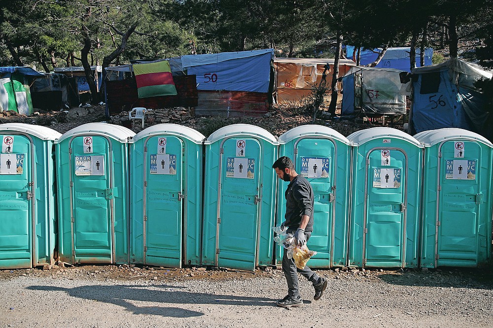 A migrant walks in front of chemical toilets outside the perimeter of the overcrowded refugee camp at the port of Vathy on the eastern Aegean island of Samos, Greece, Wednesday, Feb. 24, 2021. On a hill above a small island village, the sparkling blue of the Aegean just visible through the pine trees, lies a boy’s grave. His first ever boat ride was to be his last - the sea claimed him before his sixth birthday. His 25-year-old father, like so many before him, had hoped for a better life in Europe, far from the violence of his native Afghanistan. But his dreams were dashed on the rocks of Samos, a picturesque Greek island almost touching the Turkish coast. Still devastated from losing his only child, the father has now found himself charged with a felony count of child endangerment. (AP Photo/Thanassis Stavrakis)