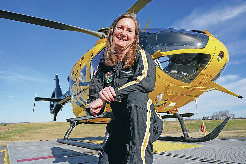 Air ambulance flight paramedic, Rita Krenz, poses in front of her company's helicopter in Weyers Cave, Va., Monday, March 15, 2021. Krenz started a fund-raising campaign that brought in more than $18,000 for the charity that has helped RIP Medical Debt forgive the debt of more than 900 people so far. (AP Photo/Steve Helber)