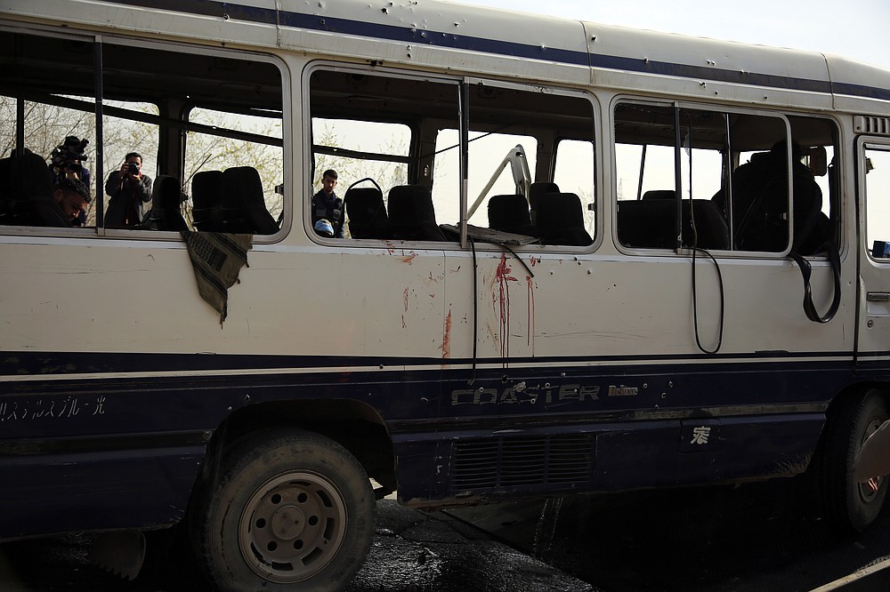 Les médias prennent une vidéo3o et des photos d'un minibus endommagé après l'explosion d'une bombe à Kaboul en Afghanistan, le jeudi 18 mars 2021. L'attaque du bus a fait de nombreux morts et blessés selon la police.  (Photo AP / Mariam Zuhaib)
