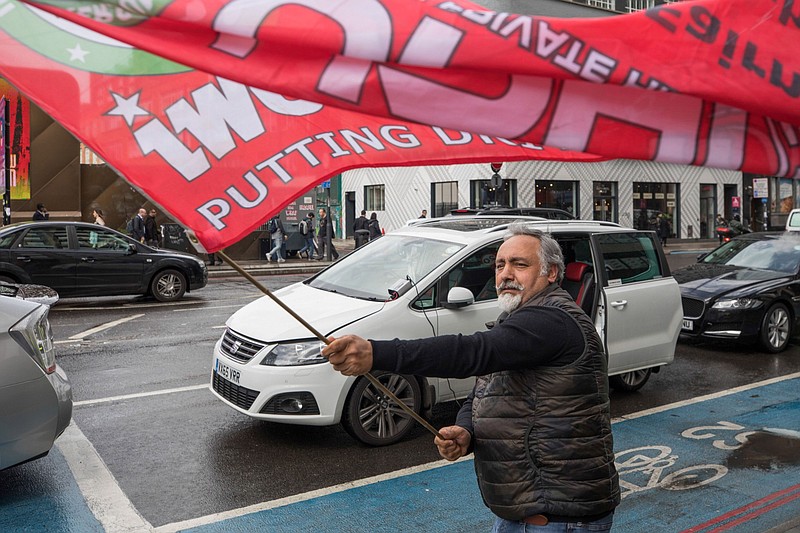 A protesting Uber driver waves a flag near the U.K. headquarters of Uber Technologies Inc. in London on May 8, 2019. MUST CREDIT: Bloomberg photo by Jason Alden.