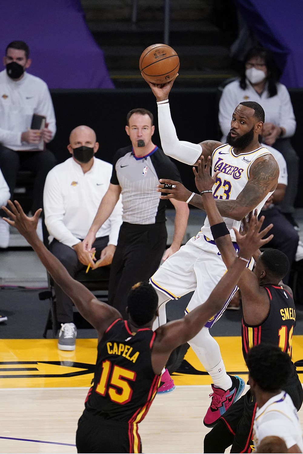 Los Angeles Lakers forward LeBron James, top, passes over Atlanta Hawks center Clint Capela (15) and forward Tony Snell during the first half of an NBA basketball game Saturday, March 20, 2021, in Los Angeles. (AP Photo/Marcio Jose Sanchez)