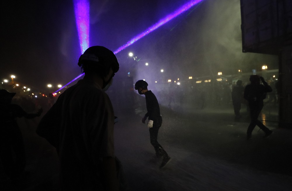 Protesters use laser lights after they were dispersed by riot police Saturday, March 20, 2021 in Bangkok, Thailand. Thailand's student-led pro-democracy movement is holding a rally in the Thai capital, seeking to press demands that include freedom for their leaders, who are being held without bail on charges of defaming the monarchy. (AP Photo/Sakchai Lalit)
