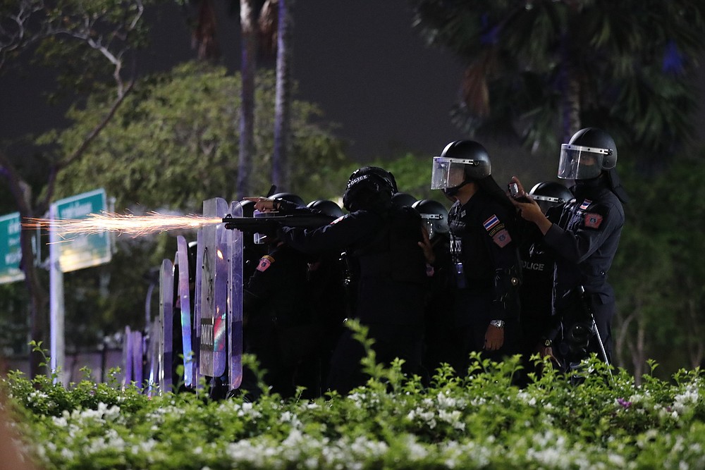 Sparks fly from the barrel of a gun used by riot police to disperse protesters who removed container vans used as a barricade in front of the Grand Palace Saturday, March 20, 2021 in Bangkok, Thailand. Thailand's student-led pro-democracy movement is holding a rally in the Thai capital, seeking to press demands that include freedom for their leaders, who are being held without bail on charges of defaming the monarchy. (AP Photo/Sakchai Lalit)