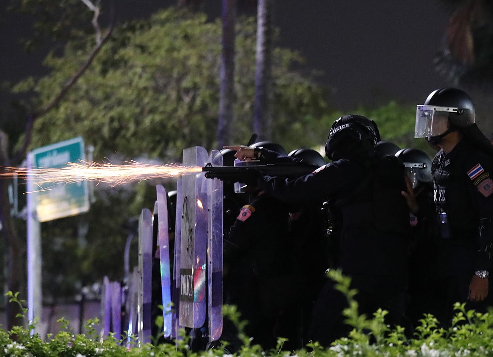 Sparks fly from the barrel of a gun used by riot police to disperse protesters who removed container vans used as a barricade in front of the Grand Palace Saturday, March 20, 2021 in Bangkok, Thailand. Thailand's student-led pro-democracy movement is holding a rally in the Thai capital, seeking to press demands that include freedom for their leaders, who are being held without bail on charges of defaming the monarchy. (AP Photo/Sakchai Lalit)