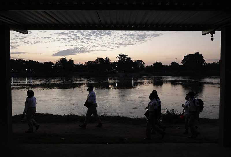 Mexican immigration agents walk towards an access point to the Suchiate River, the natural border between Guatemala and Mexico, near Ciudad Hidalgo, Mexico, Monday, March 22, 2021. Agents are enforcing new limits on all but essential travel at its shared border with Guatemala. (AP Photo/Eduardo Verdugo)