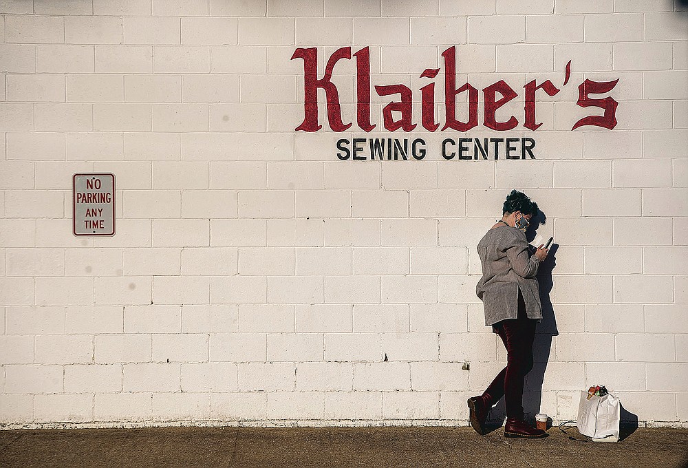 Natisha Lavender checks her phone while waiting on Klaiber's Sewing Center to open on March 3, 2021 in Bloomington, Ind. (Rich Janzaruk /The Herald-Times via AP)