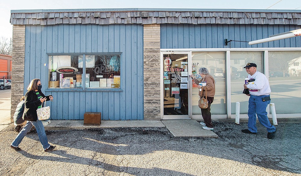 Rose Hilderbrand opens the door to Klaiber's Sewing Center as her husband Glen Hilderbrand follows as they greet employee Vonna Pheiffer before the store opens on March 3, 2021 in Bloomington, Ind. (Rich Janzaruk/The Herald-Times via AP)