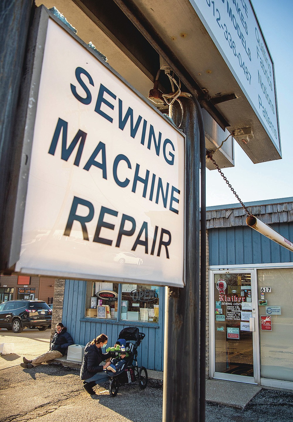 Francisco Ormaza relaxes as Stevie Sargent check on her child Bruce Sargent while waiting at Klaiber's Sewing Center to open on March 3, 2021 in Bloomington, Ind. (Rich Janzaruk /The Herald-Times via AP)