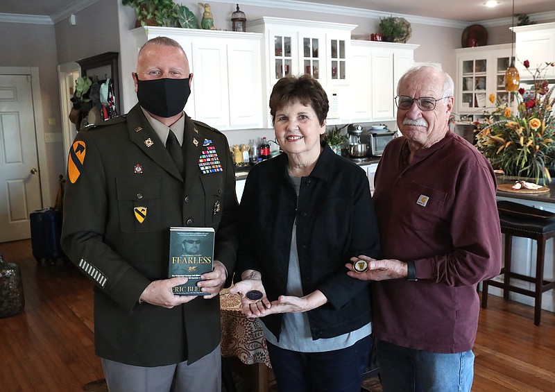 From left are U.S. Army Lt. Col. Brian Kilgore, Janice Brown and Larry Brown, after Kilgore presented two coins in honor of U.S. Navy SEAL Chief Petty Officer Adam Lee Brown to the couple on Wednesday. Kilgore is holding a copy of a book about Brown’s life. - Photo by Richard Rasmussen of The Sentinel-Record