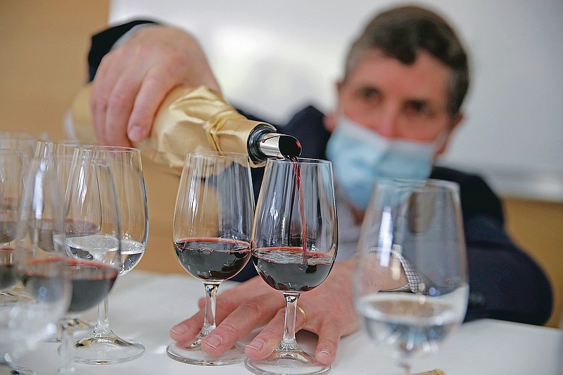 Philippe Darriet, Président of the Institute for wine and vine research and head oenologist fills glasses with wine for a blind tasting at the ISVV Institue in Villenave-d'Ornon, southwestern France, Monday, March 1, 2021. Researchers in Bordeaux are carefully studying a dozen bottles of French wine that returned to Earth after a stay aboard the International Space Station. They’re releasing preliminary results Wednesday. At a one-of-a-kind tasting this month, 12 connoisseurs sampled one of the space-traveled wines, blindly tasting it alongside a bottle from the same vintage that had stayed in a cellar. (AP Photo/Christophe Ena)
