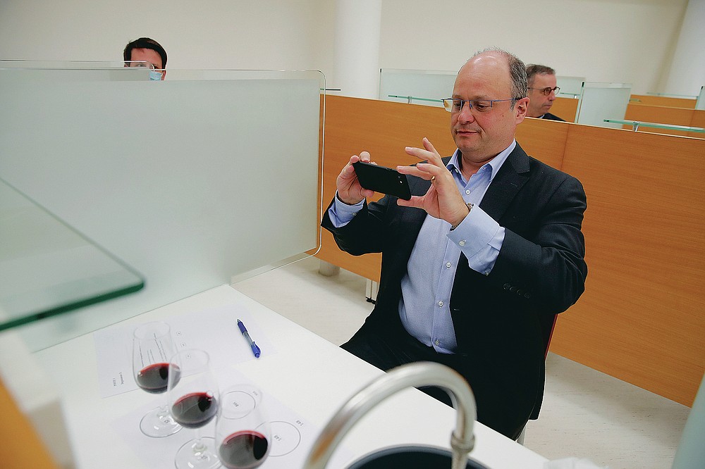 Chief Operating Officer of French National Centre for Space Studies (CNES) Lionel Suchet takes a pictures of glasses of red wine during a tasting of regular bottles and others that spent a year orbiting the world in the International Space Station, at the ISVV in Villenave-d'Ornon, southwestern France, Monday, March 1, 2021. Researchers in Bordeaux are carefully studying a dozen bottles of French wine that returned to Earth after a stay aboard the International Space Station. They’re releasing preliminary results Wednesday, March 24, 2021. At a one-of-a-kind tasting this month, 12 connoisseurs sampled one of the space-traveled wines, blindly tasting it alongside a bottle from the same vintage that had stayed in a cellar. (AP Photo/Christophe Ena)