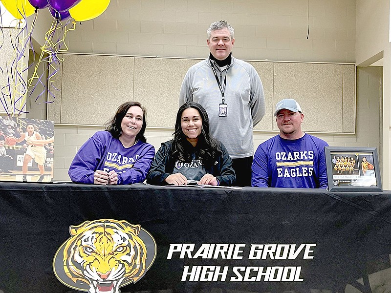 Shelley Williams Special to the Enterprise-Leader/Prairie Grove senior Jasmine Wynos (center), flanked by her parents, Aime Tackett (mom) and Jesse Tackett (dad), and accompanied by Prairie Grove girls basketball coach Kevin Froud (standing), signed a national letter of intent to play women's college basketball at University of the Ozarks.