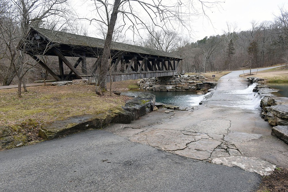 Hikers and bicycle riders cross a covered bridge. (NWA Democrat-Gazette/Flip Putthoff)