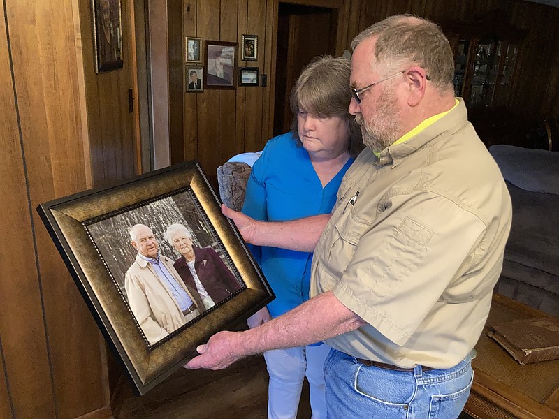 Kenneth and Debbie Staton look at a recent photograph of Kenneth's parents, Harold and Dean Staton, both of whom died from covid, just days apart. (Pine Bluff Commercial/Byron Tate)