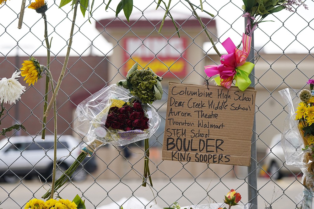 A sign listing mass shootings in Colorado hangs on the temporary fence put up around the parking lot of a King Soopers grocery store Thursday, March 25, 2021, in Boulder, Colo. Ten people were killed in a mass shooting at the supermarket earlier in the week. (AP Photo/David Zalubowski)