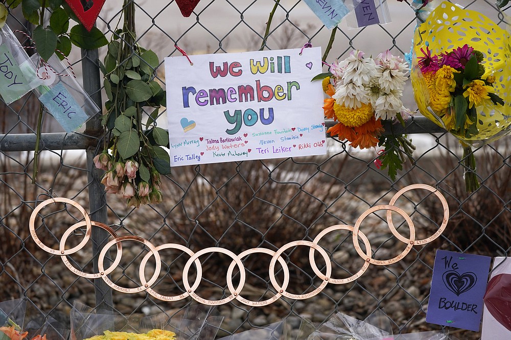 Rings inscribed with the names of the victims hang on the temporary fence put up around the parking lot of a King Soopers grocery store Thursday, March 25, 2021, in Boulder, Colo. Ten people were killed in a mass shooting at the supermarket on Monday. (AP Photo/David Zalubowski)