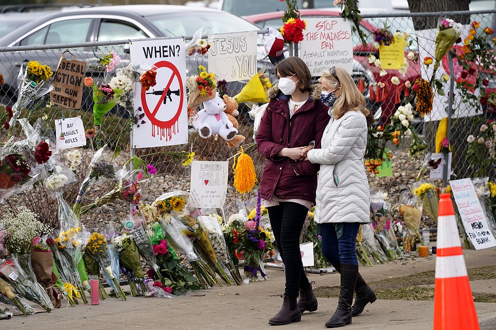Mourners walk along the temporary fence put up around the parking lot of a King Soopers grocery store where a mass shooting took place earlier in the week Thursday, March 25, 2021, in Boulder, Colo.  (AP Photo/David Zalubowski)