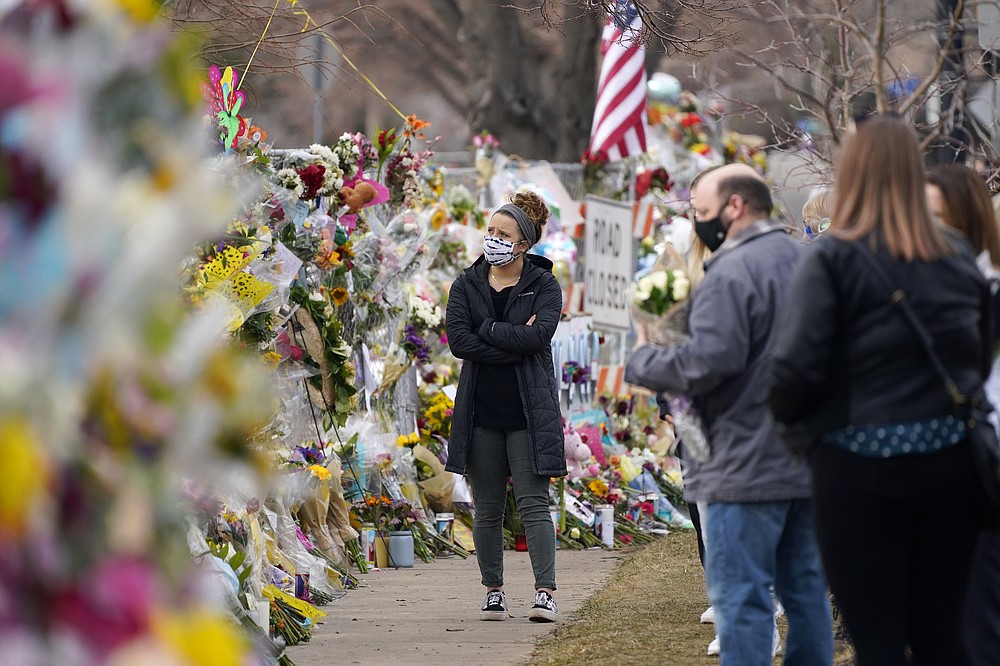 Mourners walk along the temporary fence put up around the parking lot of a King Soopers grocery store where a mass shooting took place earlier in the week, in Boulder, Colo., Thursday, March 25, 2021.  (AP Photo/David Zalubowski)