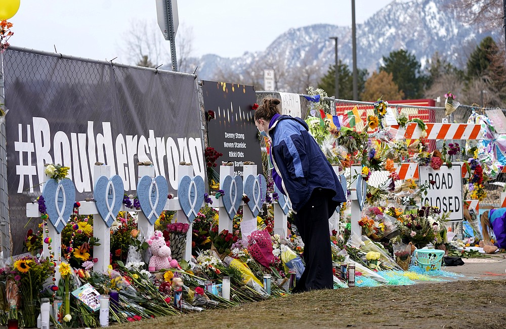 Amber Van Brocklin looks at the crosses displayed along a temporary fence set up around the parking lot of a King Soopers grocery store where a mass shooting took place earlier in the week, Thursday, March 25, 2021, in Boulder, Colo. (AP Photo/David Zalubowski)