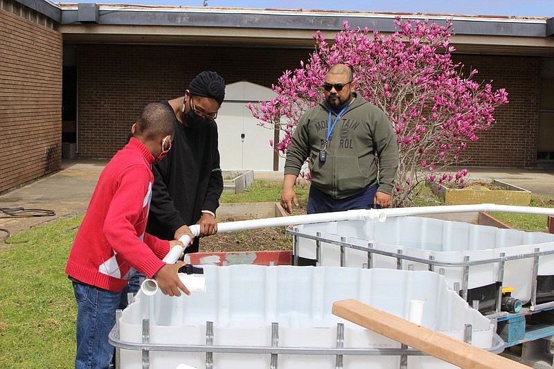 Sixth-grader Akiriam McDonald (from left) and Pine Bluff High School biology teacher Morgan Wilson are fascinated by the aquaponic garden being built at the high school by Dayan 'Dave' A. Perera, a UAPB Aquaculture & Fisheries Center’s Extension specialist, and others. (Special to The Commercial/Deborah Horn)