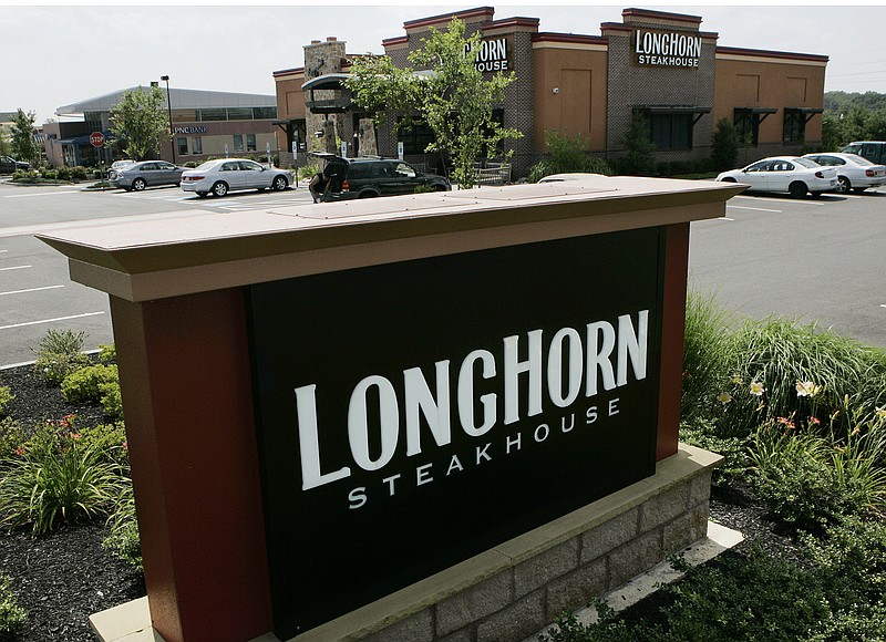 FILE - this July 21, 2008 file photo shows a Longhorn Steakhouse restaurant in Hamilton, N.J.   Darden Restaurants says every hourly employee will earn at least $10 per hour including tips starting March 29, 2021. That will rise to $12 per hour in 2023. Orlando, Florida-based Darden, which also owns LongHorn Steakhouse, Cheddar’s Scratch Kitchen and others, is also giving one-time bonuses of up to $300 to nearly 90,000 hourly employees.  (AP Photo/Mel Evans, File)