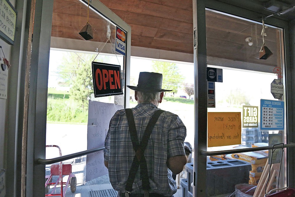 In this Monday, May 4, 2020, photo, Aaron Hurst, owner of AAA Farm Supply and member of the Old Order Groffdale Conference Mennonite Church closes his business for the day in Terre Hill, Pa. Hurst kept his hardware and animal food supply store open through the coronavirus outbreak by taking precautions such as porch pick-up service and mandatory masks. (AP Photo/Jessie Wardarski)