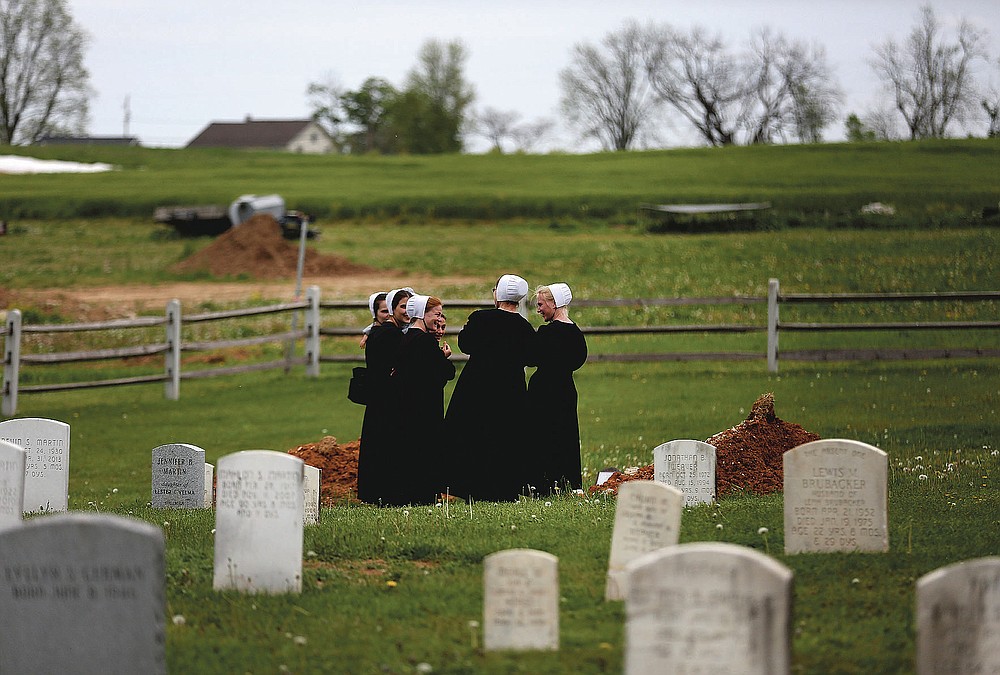 In this Sunday, May 17, 2020, photo, a group of friends visit the grave of a fellow Old Order Stauffer Mennonite member in a cemetery next to the church in New Holland, Pa. The women were among dozens of other congregants who attended the church's first in-person service since the start of the coronavirus outbreak in March. (AP Photo/Jessie Wardarski)