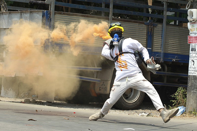 An anti-coup protester throws a smoke bomb against police crackdown in Thaketa township Yangon, Myanmar, Saturday, March 27, 2021. The head of Myanmar’s junta has used the occasion of the country’s Armed Forces Day to try to justify the overthrow of the elected government of Aung San Suu Kyi, as protesters marked the holiday by calling for even bigger demonstrations. (AP Photo)
