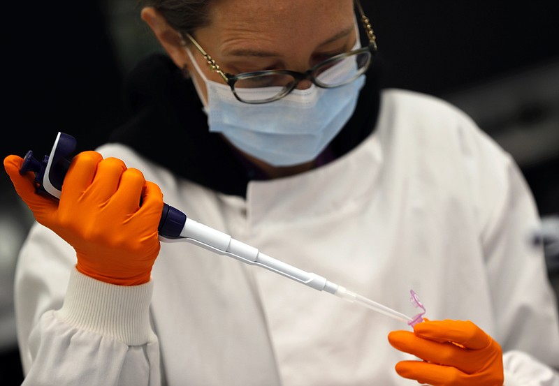 A lab assistant uses a pipette to prepare Coronavirus RNA for sequencing at the Wellcome Sanger Institute that is operated by Genome Research in Cambridge, Thursday, March 4, 2021. Cambridge University microbiologist Sharon Peacock understood that genomic sequencing would be crucial in tracking the coronavirus, controlling outbreaks and developing vaccines, so she began working with colleagues around the country to put together a plan when there were just 84 confirmed cases in the country. The initiative helped make Britain a world leader in rapidly analyzing the genetic material from large numbers of COVID-19 infections, generating more than 40% of the genomic sequences identified to date.(AP Photo/Frank Augstein)