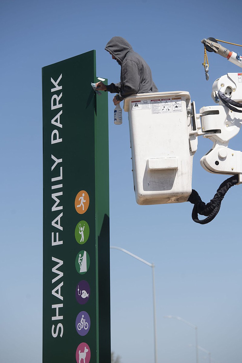 Chase Wilhite of Centerton cleans a sign Monday March 29, 2021 at the Shaw Family Park in Springdale. Wilhite works for Best Sign Group, the company that installed all the signs at the park. (NWA Democrat-Gazette/J.T. Wampler)