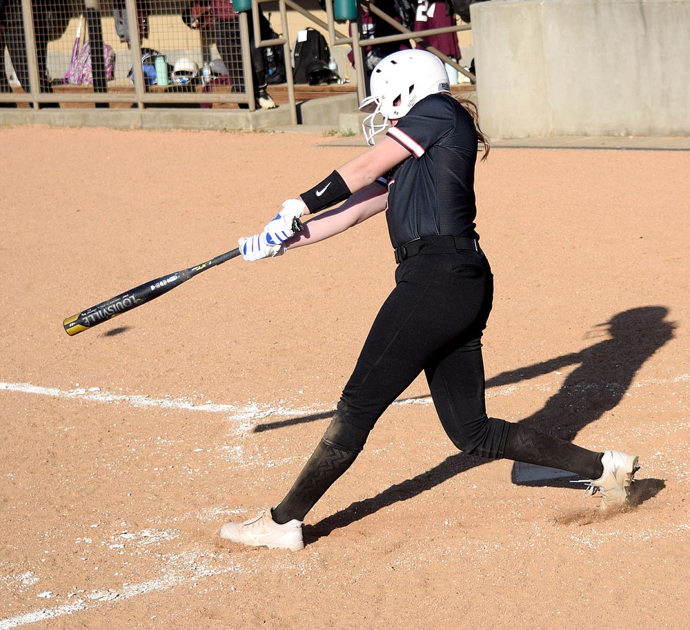 Westside Eagle Observer/MIKE ECKELS
The shadow of the ball (under top of bat) is cast on the ground for a split second after Lady Lion Brooke Handle blasted it over the left field wall during the fourth inning of the Gravette-Siloam Springs softball game in Gravette Thursday night. Handle brought home two base runners for a three run home run which contributed to the 11-1 Lady Lions victory over the Lady Panthers.