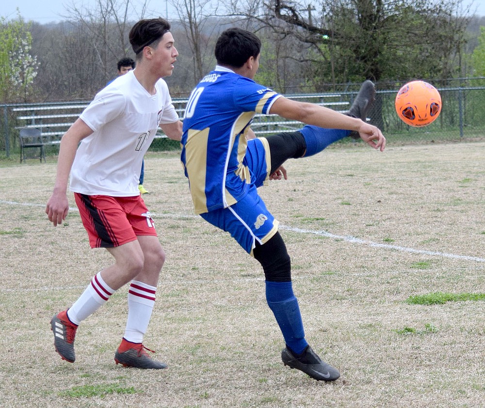 Westside Eagle Observer/MIKE ECKELS
Andres Revolorio (Decatur 10) kicks the ball away from a Highlander player and sending it to the front line for a Bulldog shooting attempt during the second half of the Decatur-Eureka Springs conference soccer match in Decatur March 30. The Bulldogs took the win 6-1 in the first home contest at Bulldog Stadium.