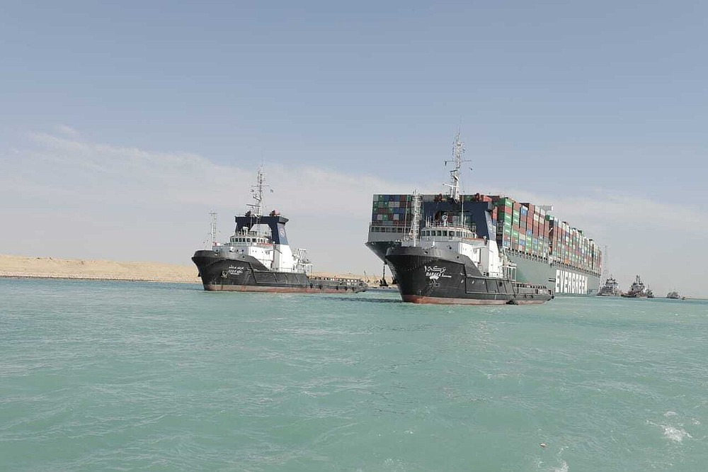 In this photo released by Suez Canal Authority, the Ever Given, a Panama-flagged cargo ship is accompanied by Suez Canal tugboats as it moves in the Suez Canal, Egypt, Monday, March 29, 2021. Salvage teams on Monday set free a colossal container ship that has halted global trade through the Suez Canal, bringing an end to a crisis that for nearly a week had clogged one of the world's most vital maritime arteries. (Suez Canal Authority via AP)