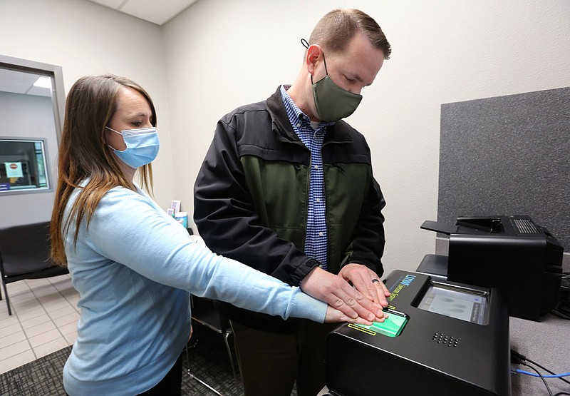 Lt. Randy Wood, with the Bentonville Police Department, pulls a series of fingerprints Tuesday from Tiffany Steal, records supervisor, as they demonstrate the fingerprinting device currently in use at the Police Department that is no longer supported by the provider, Secure Outcomes, that is out of business according to the city. The Bentonville City Council should approve buying two new fingerprinting computers for the Police Department on Tuesday night. The equipment will come from IDEMIA Identity and Security USA LLC. One device will be for the detention/booking area to transmit mandated arrestee prints to the Arkansas State Police√¢‚Ç¨‚Ñ¢s automated fingerprint identification system for criminal history tracking, and the other will provide fingerprinting services to the public for various state licensing requirements, background checks, adoptions and conceal carry licenses, according to city documents. The computers are the same used by automated fingerprint identification system and allows fingerprints to be sent electronically to the State Police. Check out nwaonline.com/210331Daily/ and nwadg.com/photos for a photo gallery.
(NWA Democrat-Gazette/David Gottschalk)