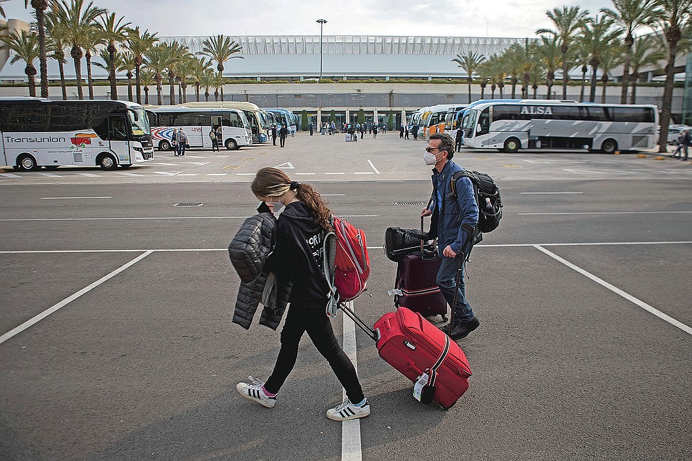 Passengers wearing face masks arrive at Palma de Mallorca Airport on the Spanish Balearic Island of Mallorca, Spain, Saturday, March 27, 2021. Efforts in Spain to restart tourism activity is drawing a mixed picture due to a patchwork of national, regional and European rules on travel that is confusing both tourists and their hosts. (AP Photo/Francisco Ubilla)