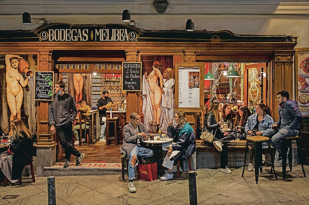 Tourists and locals have drinks at a bar in downtown Madrid, Spain, Friday, March 26, 2021. With its policy of open bars and restaurants, Madrid has built itself a reputation of something like Europe's last reduct for fun. That's driving some business to locals and giving politicians and the media much to debate about ahead of a regional election. (AP Photo/Bernat Armangue)