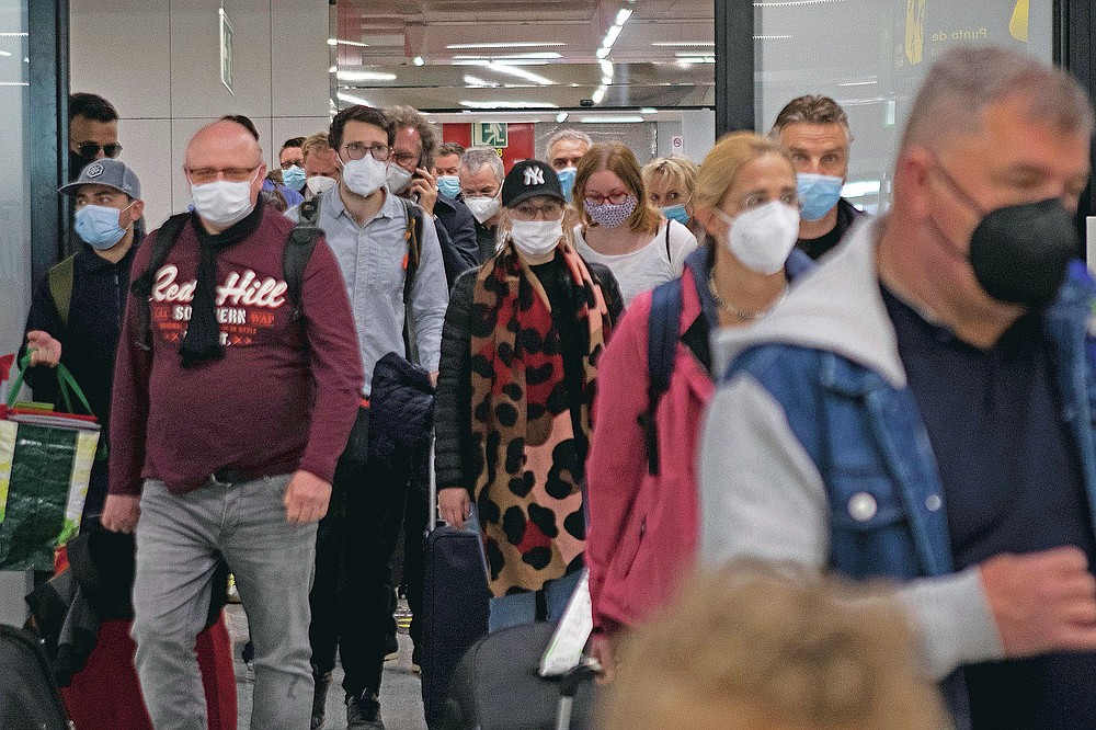 Passengers wearing face masks arrive at Palma de Mallorca Airport on the Spanish Balearic Island of Mallorca, Spain, Saturday, March 27, 2021. Efforts in Spain to restart tourism activity is drawing a mixed picture due to a patchwork of national, regional and European rules on travel that is confusing both tourists and their hosts. (AP Photo/Francisco Ubilla)