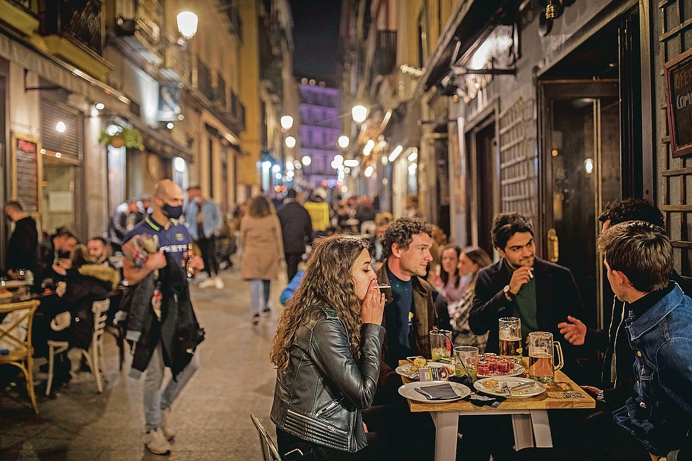 Tourists and locals have drinks at a bar in downtown Madrid, Spain, Friday, March 26, 2021. With its policy of open bars and restaurants — indoors and outdoors — and by keeping museums and theaters running even when outbreaks have strained hospitals, Madrid has built a reputation as an oasis of fun in Europe’s desert of restrictions. Other Spanish regions have a stricter approach to entertainment. Even sunny coastal resorts offer a limited range of options for the few visitors that started to arrive, coinciding with Easter week, amid a set of contradictory European travel rules. (AP Photo/Bernat Armangue)